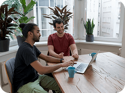 Two teammates chatting over a laptop