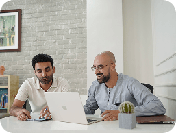 Two teammates reviewing work on a laptop